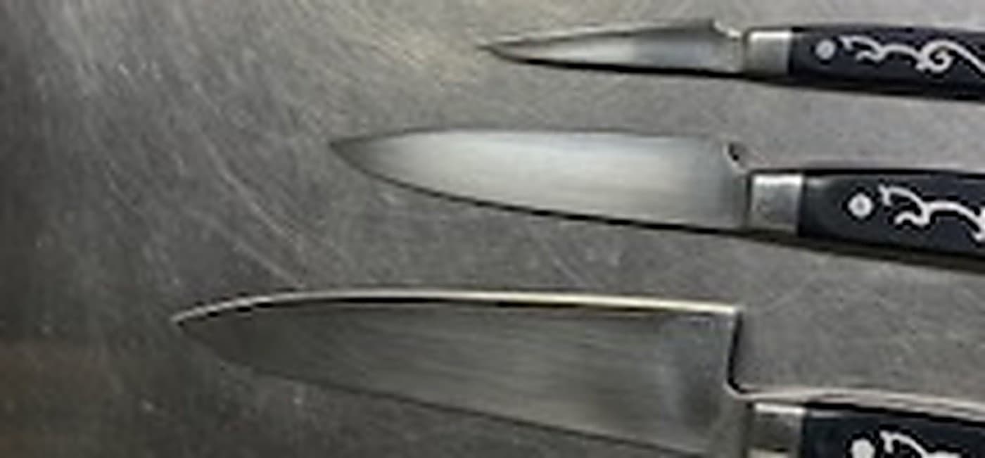 Close-up of knife edges before sharpening showing visible damage and dull spots.